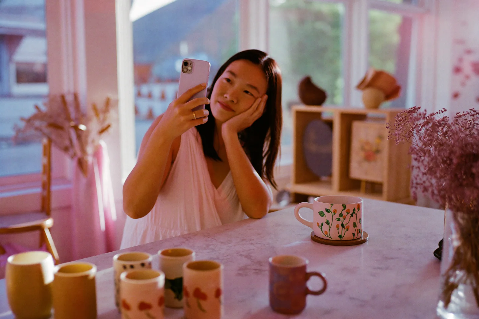 A person sitting at a café counter absorbed in their phone, warm afternoon light across the room, illustrating the roughly 32 minutes a day the average user spends on Instagram